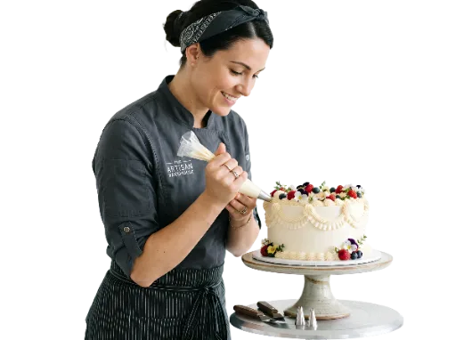 Female pastry chef decorating a frosted cake with a piping bag